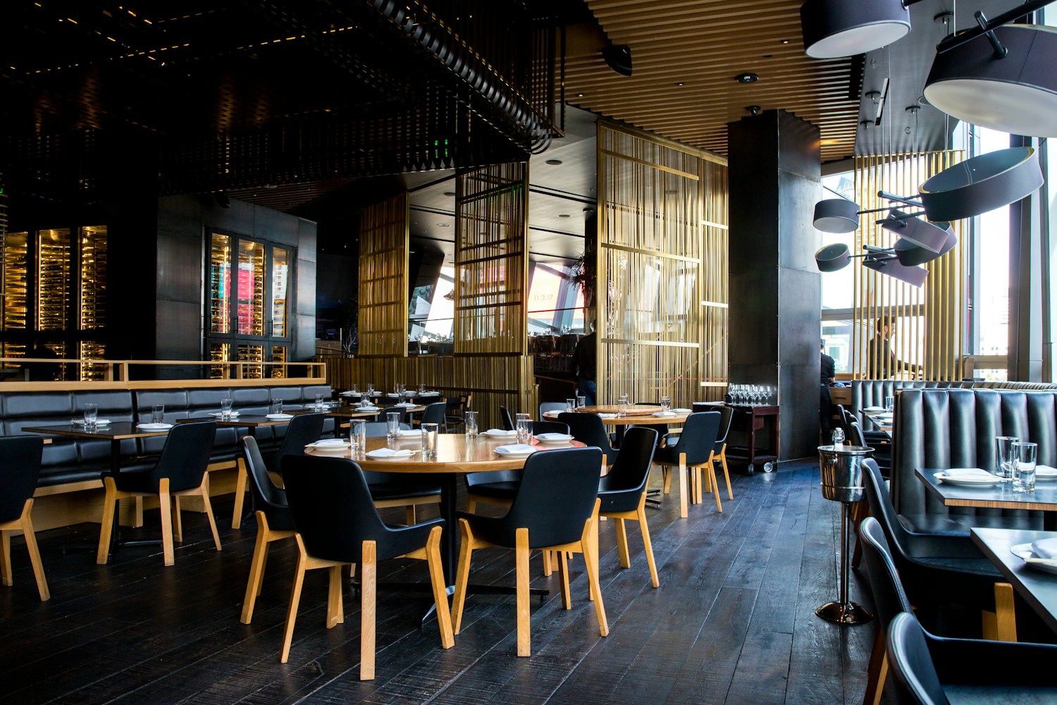 A warm restaurant interior with pendant lights and greenery